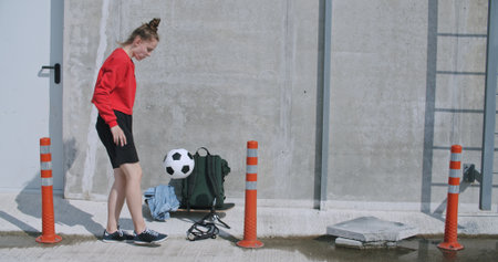 Teenager girl football soccer player doing ball tricks on rooftop empty parking garage. Urban city...