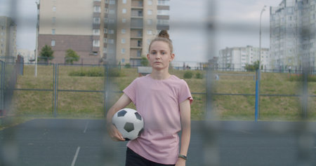Young caucasian girl practicing soccer skills and tricks, holdind a soccer ball in her hands. Urban city lifestyle outdoors conceptの写真素材