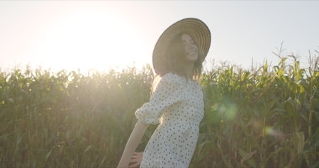 Happy young woman in straw hat standing againstcorn stalks looking at camera and smilingの写真素材