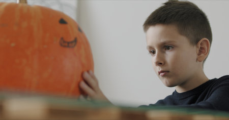 Close-up of kid drawing halloween holiday decoration on punpkin .の写真素材