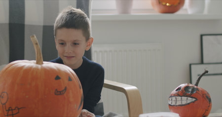 Close-up of kid drawing halloween holiday decoration on punpkin .の写真素材