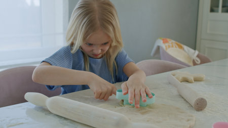 girl rolling dough on kitchen table