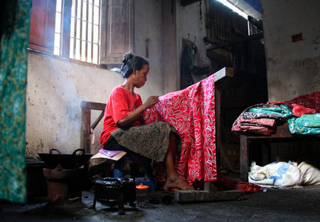 A woman making traditional batik cloth at home