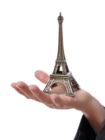 Closeup of a hand showing a tiny Eiffel Tower isolated on white backgroundの写真素材