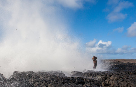 Man watches an big wave splash on rock in a stormy weather at Atlantic sea cost の写真素材