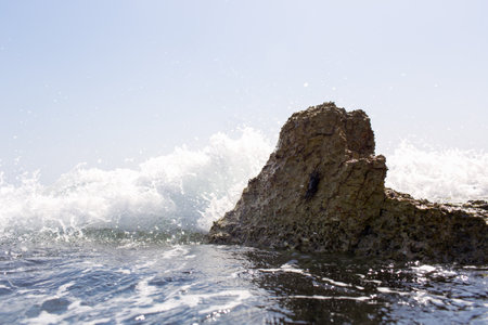 Sea wave splashing over the shore rocks with a high sea sprayの写真素材
