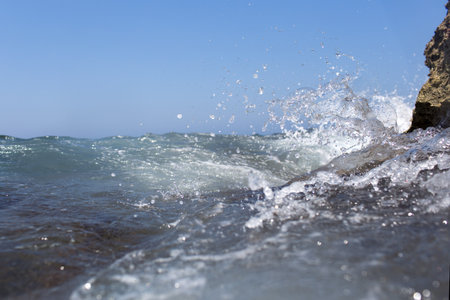 Sea wave splashing over the shore rocks with a high sea spray