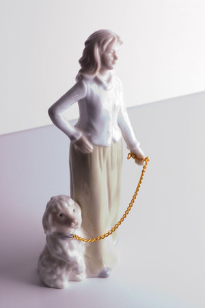 Figurine walking a dog with a gold chainの写真素材