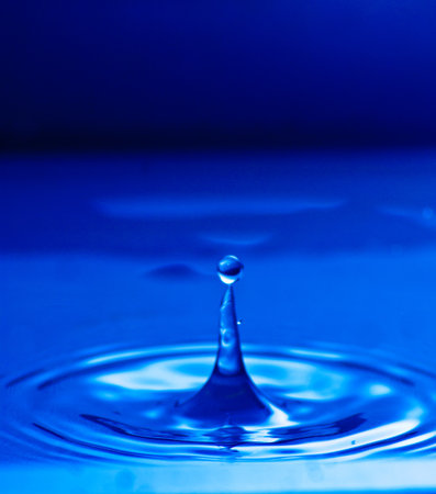 Water drop landing into a puddle surfaceの写真素材