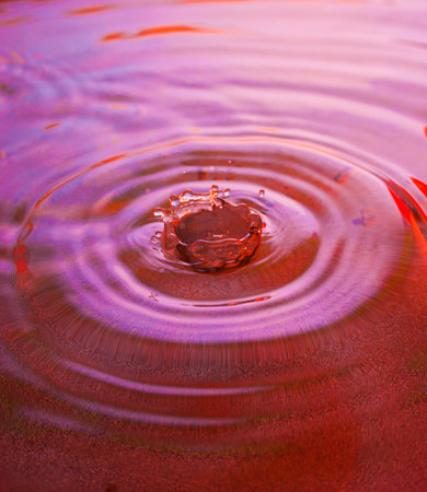 Water drop landing into a puddle surfaceの写真素材
