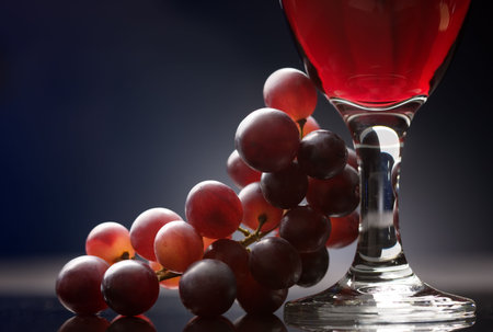 Close-up of a glass of red wine with grapes on a tableの写真素材