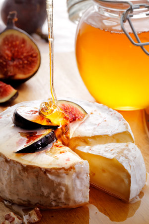 Brie Cheese and sliced Figs poured with honey on wood cheeseboardの写真素材