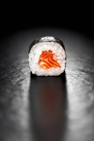 Maki Sushi Roll with Salmon and Rice wrapped in Nori on a black backgroundの写真素材