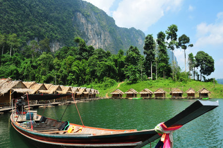 Tropical lakeside hut and wooden boat in ratchaprapa Dam,Khao Sok,Thailand の写真素材