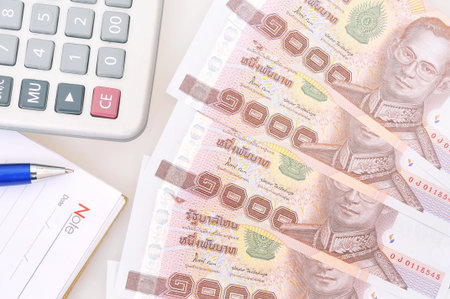 Calculator and pen on thai banknotesの写真素材