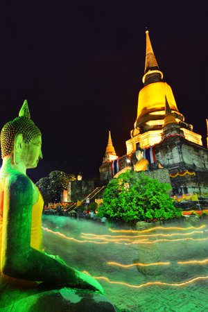 People hold candle light walking past the front of pagoda in Wian Tian ceremony. Wesak or Vesak also known as Buddha Purnima and Buddha Day.Part of the ruin of Wat Yai Chai Mongkol in Ayutthaya.のeditorial素材