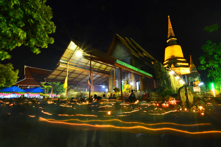 People hold candle light walking past the front of pagoda in Wian Tian ceremony. Wesak or Vesak also known as Buddha Purnima and Buddha Day.Part of the ruin of Wat Yai Chai Mongkol in Ayutthaya.のeditorial素材