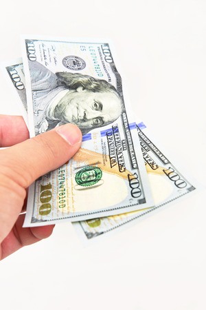 A man's hand holding one hundred dollar bill.