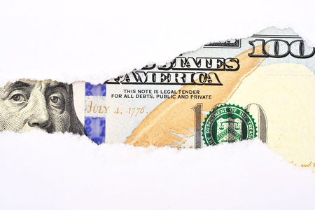 Benjamin Franklin macro peeking through torn white paper.の写真素材