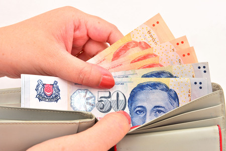 wallet with singapore dollars in the hands on a white backgroundの写真素材
