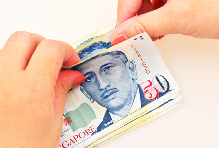 Singapore dollars in the hands on a white background,counting.