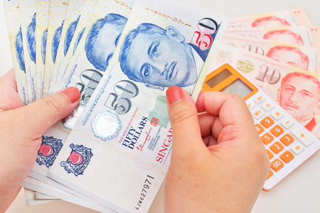 Singapore dollars in the hands on a white backgroundの写真素材