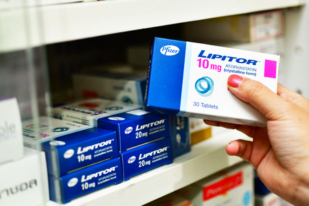 Bangkok,Thailand - March 5, 2018 : Pharmacist holding a medicine Lipitor box for hight blood lipid and leaflet in pharmacy drugstore.のeditorial素材