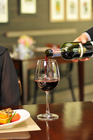 Red wine pouring into wine glassの写真素材