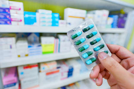 Hand holding medicine capsule pack at the pharmacyの写真素材