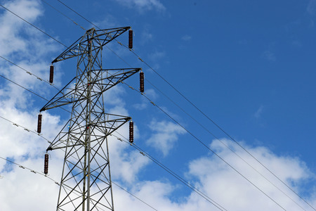 High voltage electricity pylon or power transmission tower with cables. Blue sky with white clouds...