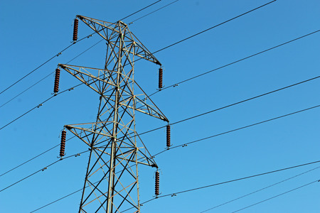 High voltage electricity pylon or power transmission tower with cables. Blue sky in the background....