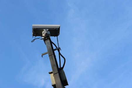 CCTV camera on metal square column with blue sky and light clouds in the background.の写真素材