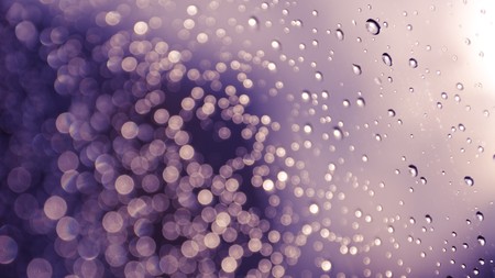 blurred rain drops on glass with a purple background