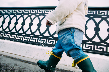 child walks through the puddles in rubber bootsの写真素材