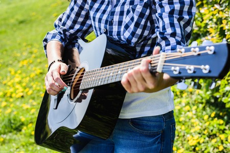 woman playing an acoustic guitar black, close-up