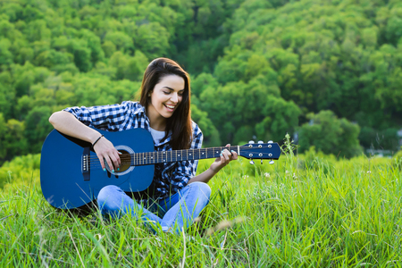 woman playing acoustic guitar in the natureの写真素材