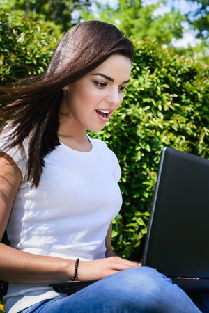 Woman resting on the lawn looking at laptopの写真素材