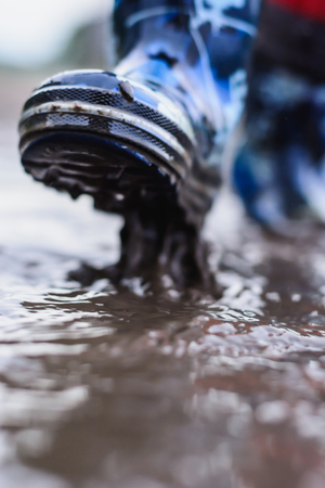 colored waterproof boots in a puddle closeup
