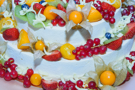 three-tiered white cake with fruits and berries