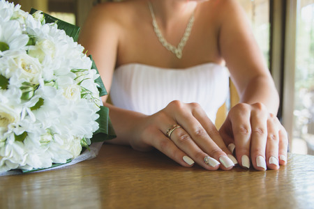 girl showing her wedding manicure at the tableの写真素材