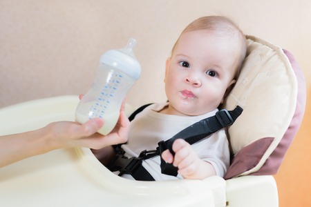 toddler sitting at the table and drinking milkの写真素材