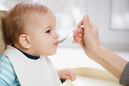 baby eating from a spoon eats milk porridgeの写真素材