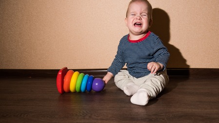 naughty little baby sitting near the wallの写真素材