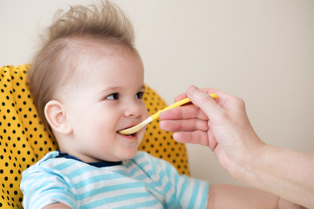 baby eating from a spoon eats milk porridgeの写真素材