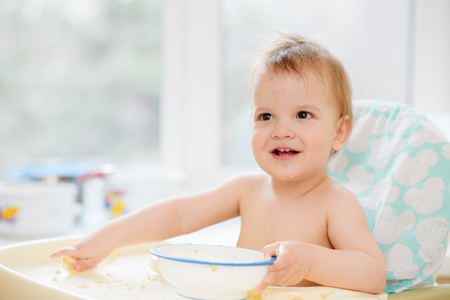 Kid plays in the kitchen with dishesの写真素材