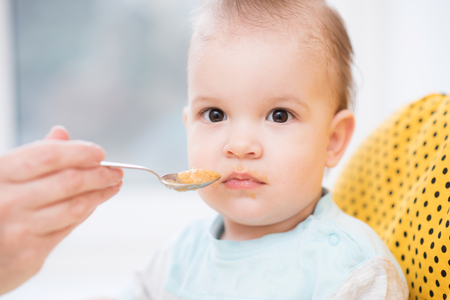 baby eating from a spoon eats milk porridgeの写真素材