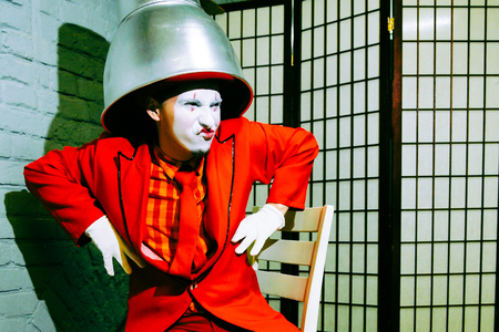 Mime put a metal lampshade on his head, makes faces and depicts someoneの写真素材