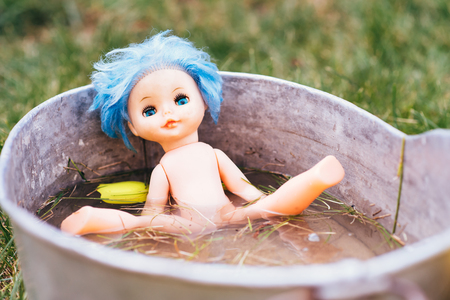 an abandoned doll in a basin of waterの写真素材