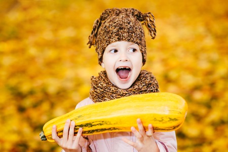 girl in the autumn Park holding a pub and wants him to biteの写真素材
