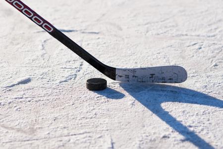 close-up stick and puck on the ice background
